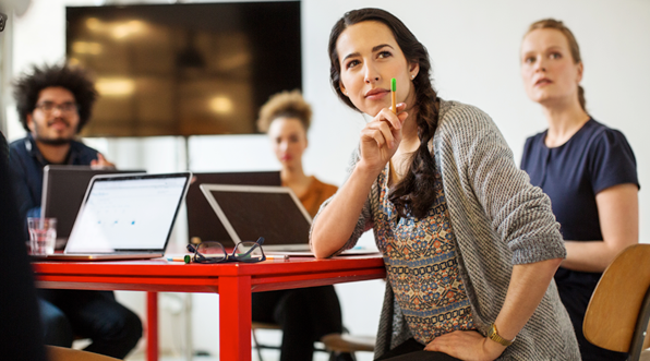 A woman sitting at a table with her laptop, working on a project.